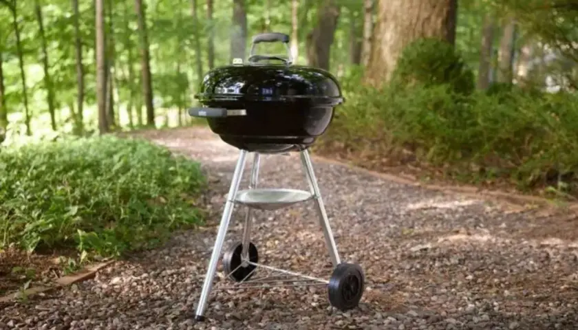 Barbecue noir avec couvercle, prêt pour un repas en plein air. Apprenez comment utiliser un barbecue avec couvercle pour des grillades parfaites.