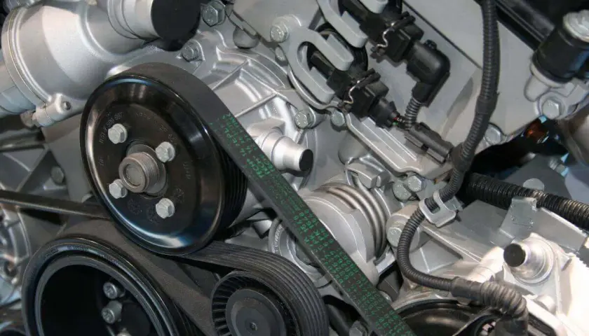 Detalle del motor de un coche, mostrando la polea y la correa de distribución.