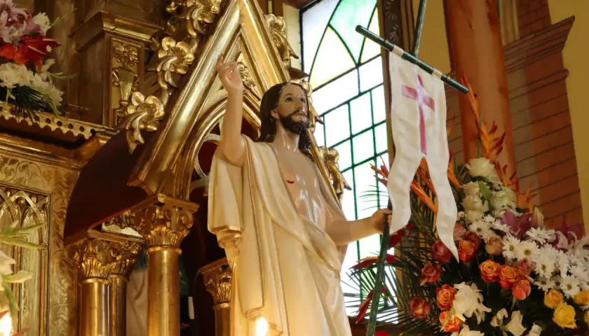 Figura Jezusa z chorągwią z krzyżem, otoczona złotymi zdobieniami i kwiatami. Symbolizuje zwycięstwo i nadzieję, przypominając o tym, ile trwaja rezurekcje.