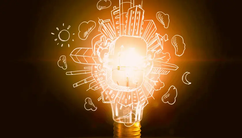 Bombilla encendida con dibujos de ciudad, sol y luna. Representa la diferencia entre potencia y energía, la chispa de una idea.