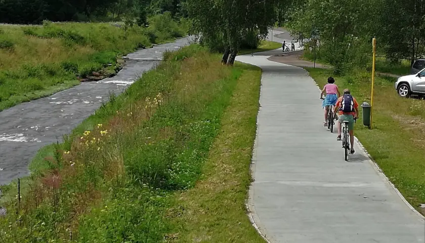 Rowerzyści na ścieżce wzdłuż potoku. Velo Krynica zaprasza do aktywnego wypoczynku na łonie natury.
