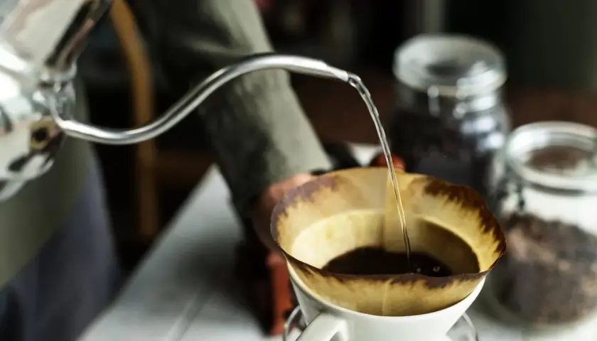 Preparazione di un v60 caffè: acqua calda versata lentamente su caffè macinato in un filtro di carta.