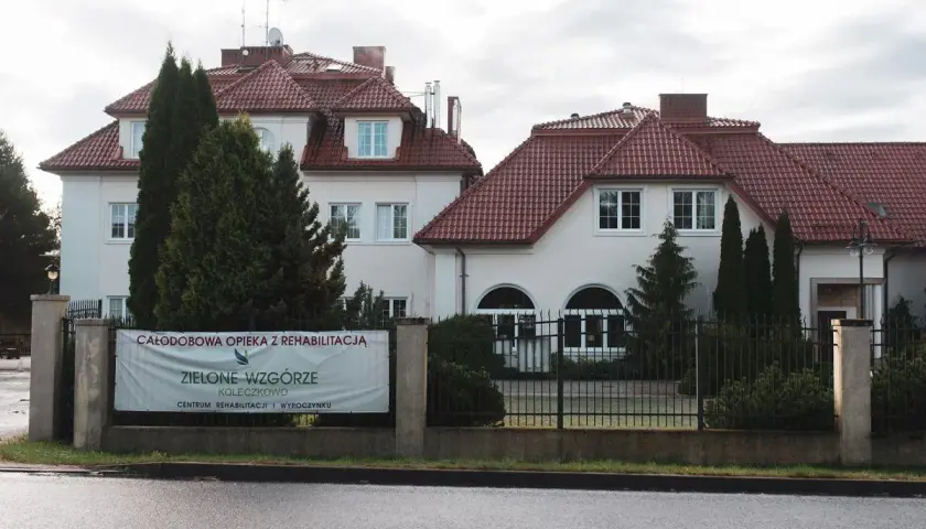 Budynek z czerwonym dachem i banerem "Zielone Wzgórze".