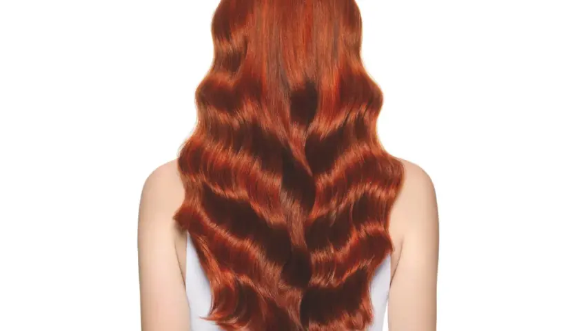 Una melena ondulada y brillante de pelo cobrizo natural, con reflejos dorados que capturan la luz.