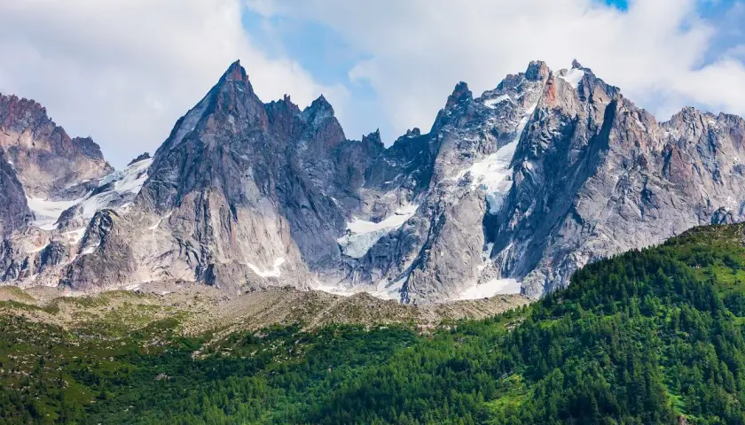 Majestatyczne szczyty Mont Blanc latem, z zielonymi zboczami i resztkami śniegu.