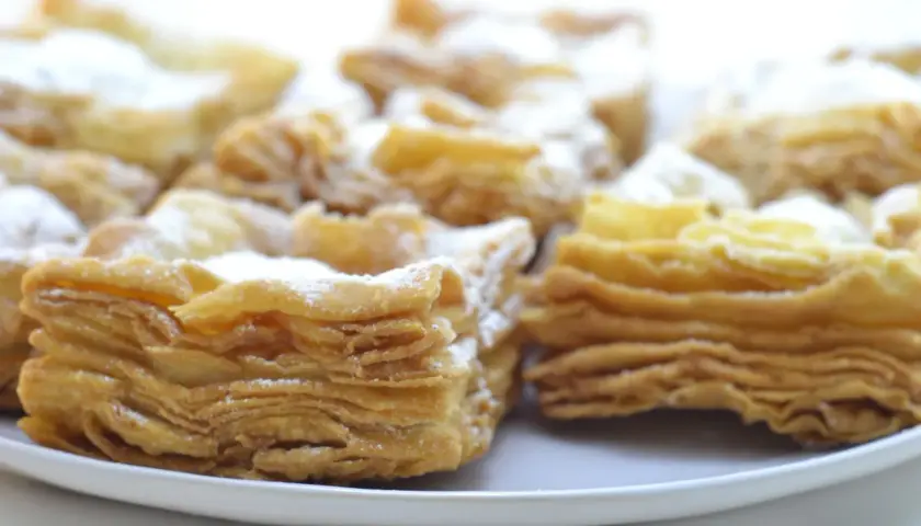 Deliciosos pastelitos de hojaldre con azúcar glas. El hojaldre, con sus capas crujientes y doradas, invita a probarlos.