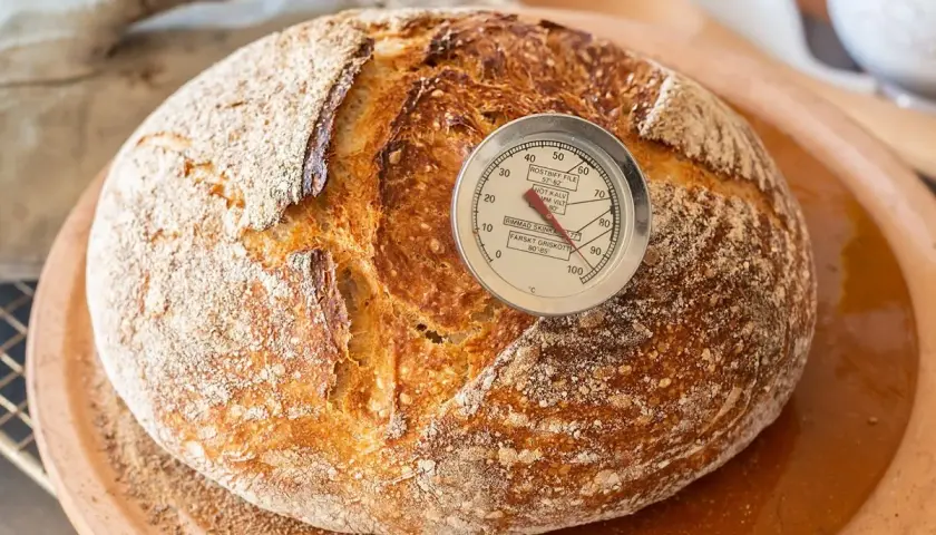 Pan artesanal recién horneado, listo para disfrutar. El termómetro indica la temperatura perfecta para hacer pan con masa madre.