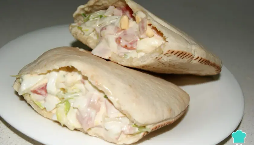 Dos deliciosos bocadillos de pan pita rellenos de ensalada cremosa, jamón y huevo.