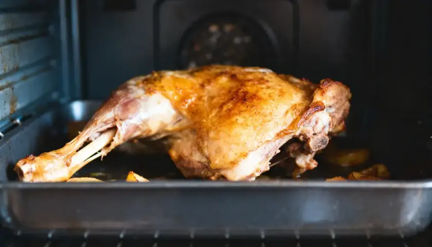 Un gigot d'agneau doré et juteux cuit dans un plat au four, prêt à être dégusté.