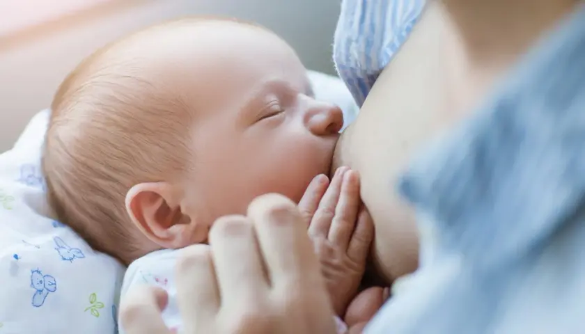 Malutkie rączki otulają pierś mamy. Karmienie piersią to piękny moment, w przeciwieństwie do palenia papierosów, które szkodzi dziecku.