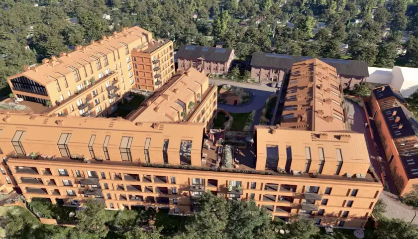 Nowoczesne budynki mieszkalne nawiązujące architekturą do historycznego folwarku Scheiblera. Widać ceglane elewacje, spadziste dachy i zielone dziedzińce.