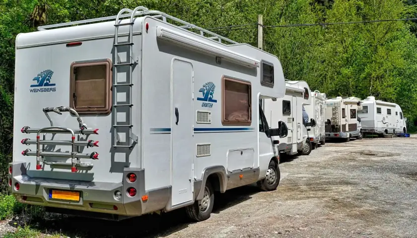 Une file de camping-cars blancs garés dans un paysage verdoyant, prêts pour une aventure à Marseille.
