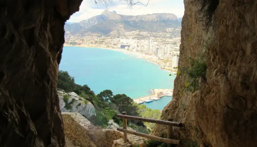 Camino rocoso para subir al Peñón de Ifach, con vistas al mar turquesa y la ciudad.