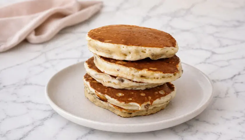 Pile de pancakes banane moelleux, dorés et aérés, servis sur une assiette claire.