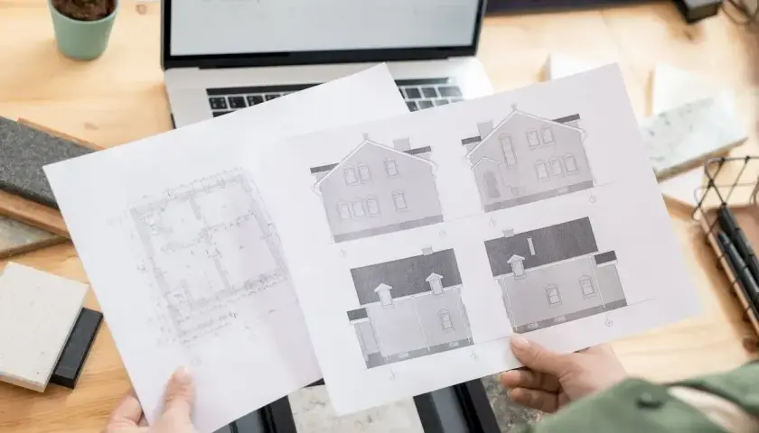 Architekt analizuje plany domu, zastanawiając się, ile trzeba czekać na pozwolenie na budowę.