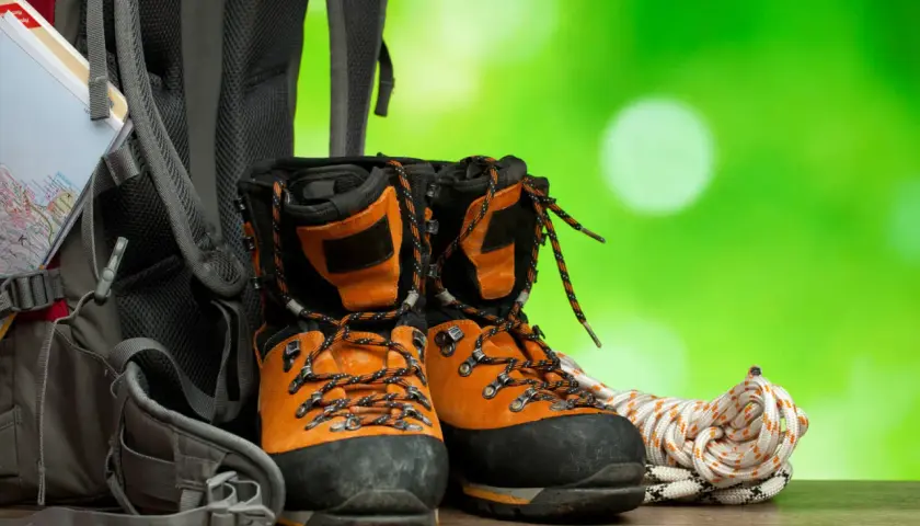 Pomarańczowe buty trekkingowe, plecak i lina. Zadbaj o nie, używając impregnatu do butów z membraną, by były gotowe na każdą wyprawę.