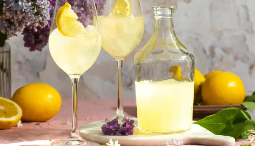 Erfrischender Limoncello Spritz mit Zitronenscheiben, Eis und Flieder.