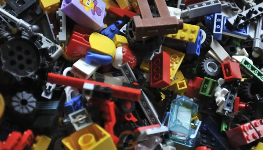 Bunte LEGO Steine sortieren: Ein Haufen verschiedener Bausteine, Räder und Figuren wartet darauf, zu neuen Welten zusammengefügt zu werden.
