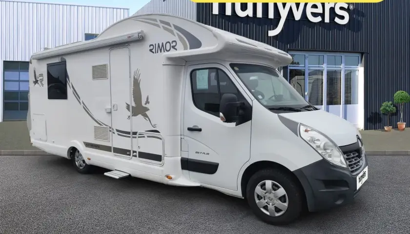 Un camping-car Rimor Katamarano 109 Plus blanc, avec un aigle stylisé sur le flanc, prêt pour l'aventure.