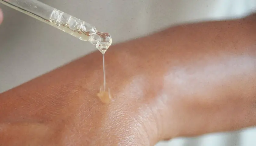 Kropla serum z niacynamidem na skórze. Zobacz, jak działa niacynamid, nawilżając i poprawiając jej wygląd.