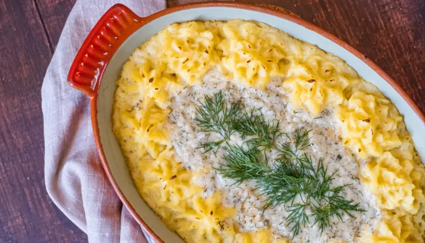 En krämig vegetarisk fisksås med potatismos och dill i en ugnsform.