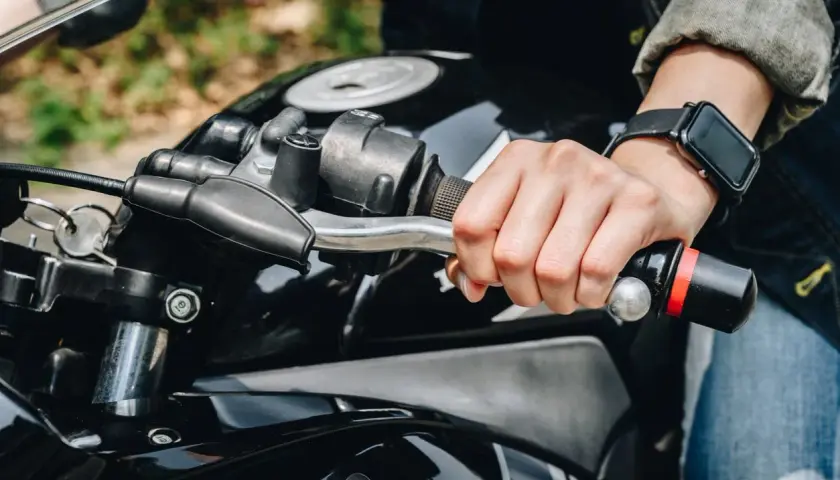 Mano sujetando el manillar de una moto, lista para accionar el freno motor.
