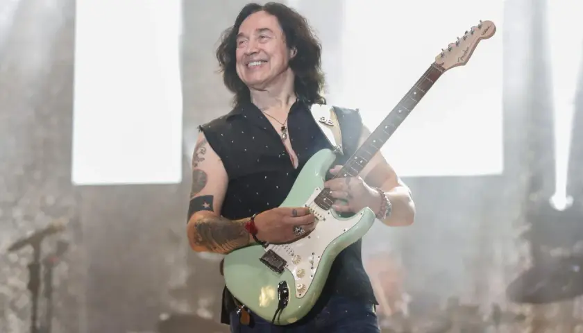 Jan Borysewicz z Lady Pank gra na gitarze, uśmiechając się do publiczności.
