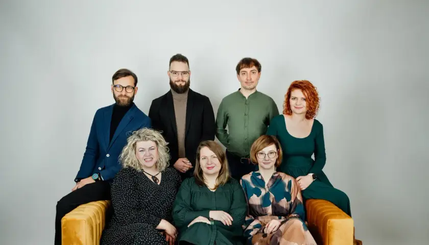 Grupa siedmiu psychoterapeutów, cztery kobiety i trzech mężczyzn, pozuje do zdjęcia na kanapie.