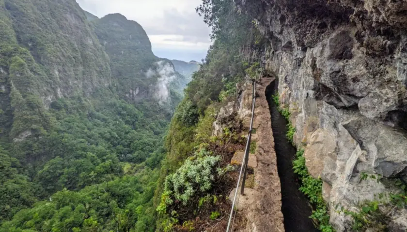 Ein schmaler Weg entlang eines Kanals führt durch eine Schlucht auf Madeira. Die Levadas Madeira sind ein beeindruckendes Wandererlebnis.