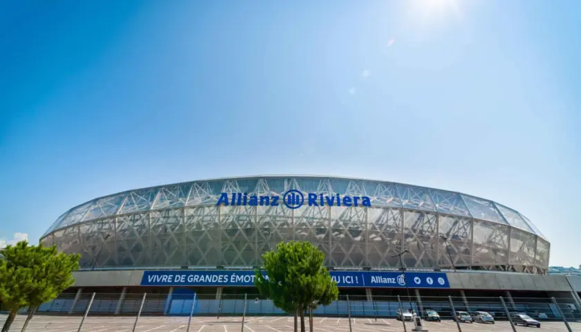 Nowoczesny stadion Allianz Riviera w Nicei, z charakterystycznym, przeszklonym dachem i niebieskim napisem.