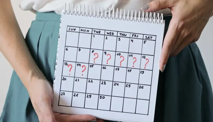 Kalender mit roten Fragezeichen, die auf unregelmäßige Zyklen und den Zusammenhang zwischen **Stress und Periode** hinweisen.