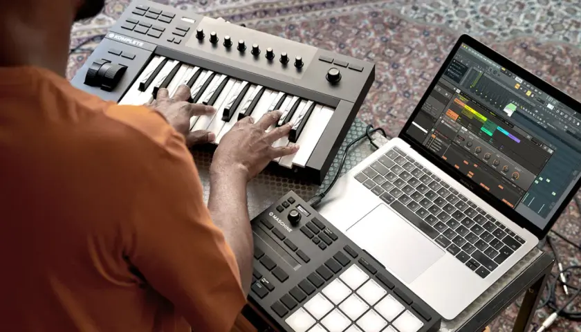 Ein beat producer arbeitet an seinem Laptop mit Musiksoftware und spielt auf einem MIDI-Keyboard.