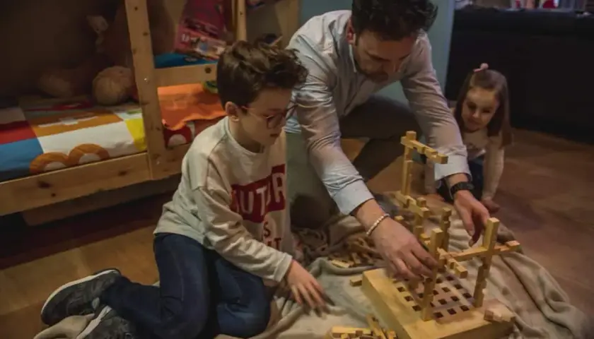 Padre e hijos construyen con bloques de madera, creando sus propios juguetes Waldorf caseros.