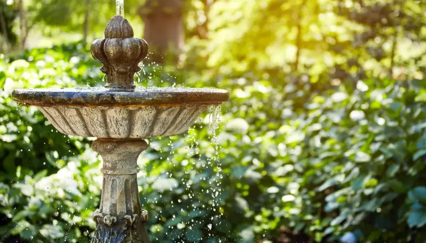 Ein antiker Gartenbrunnen sprudelt im Sonnenlicht. Tolle Ideen für Brunnen im Garten, die Ruhe und Schönheit bringen.