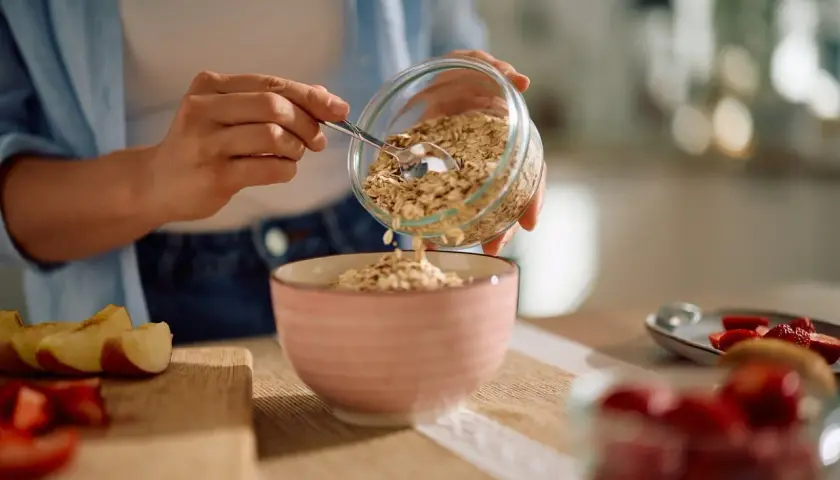 Préparation d'un petit-déjeuner sain avec des flocons d'avoine, rappelant le bon rendement avoine hectare. Des fruits frais sont à proximité.