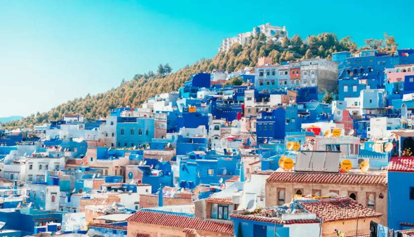 Widok na niebieskie i białe budynki miasta Chefchaouen w Maroku, na tle wzgórza.