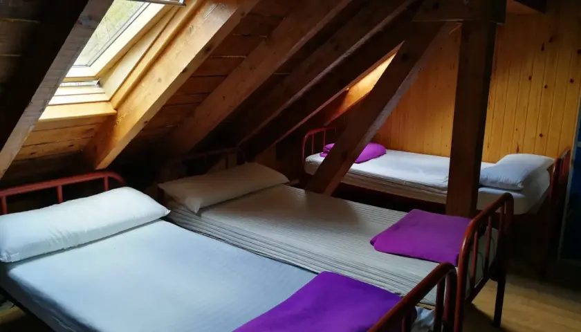 Refugio con ángulos de madera y camas sencillas, listo para recibir a viajeros.