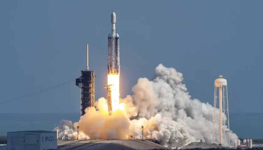 Rakieta Falcon Heavy SpaceX startuje, wzbijając się w niebo z potężnym płomieniem i kłębami dymu.