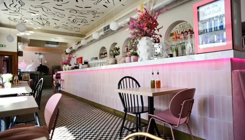 Stylowe wnętrze restauracji w Warszawie z różowym neonem i czarno-białą szachownicą na podłodze. Idealne miejsce na listę "top 10 restauracji Warszawa".