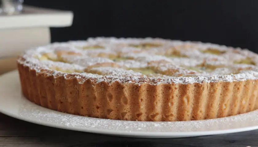Una deliziosa crostata di ricotta, cosparsa di zucchero a velo, pronta per essere gustata.