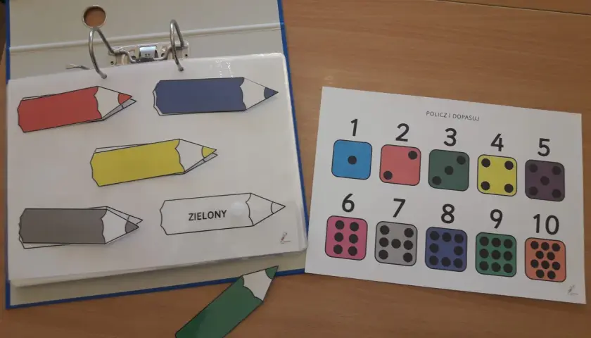 Kolorowe kredki i kostki do gry na karcie "Policz i dopasuj" to część edukacyjnych książeczek aktywizujących.