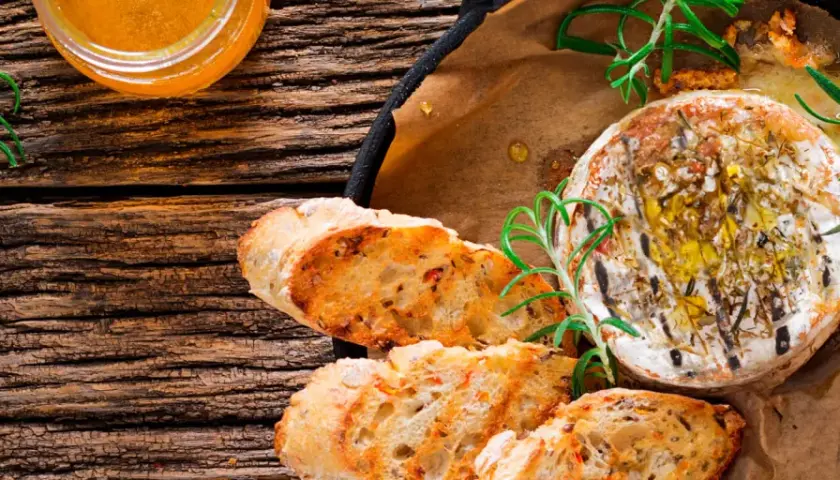 Un délicieux fromage au barbecue, doré et fondant, servi avec du pain grillé et du romarin frais.
