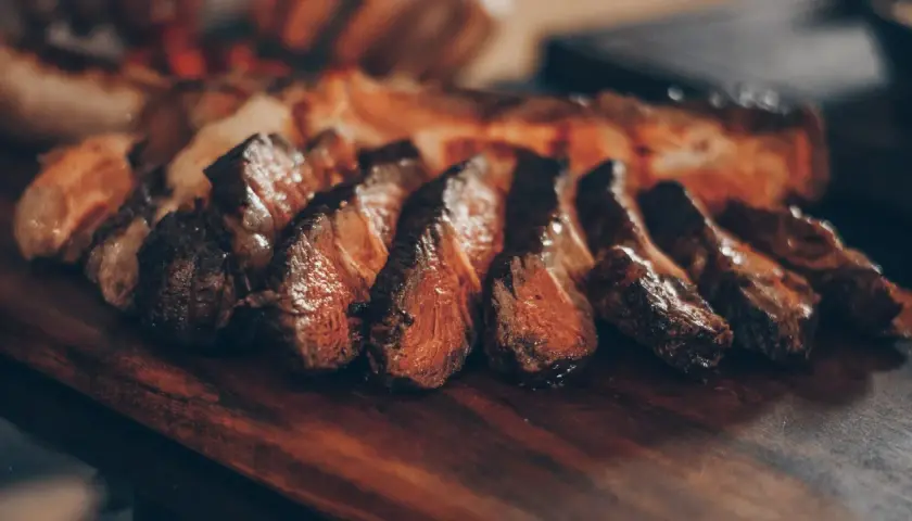 Tranches de viande juteuse sur une planche en bois. Idéal pour savoir quel vin servir avec une pierrade de viande.