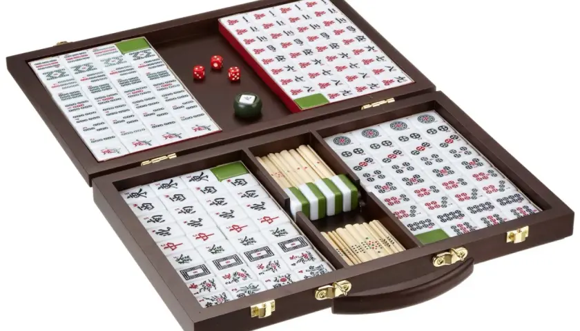 Ein Mahjong-Set in einem Holzkoffer, bereit für spannende japanische Brettspiele. Würfel und Spielsteine sind übersichtlich angeordnet.