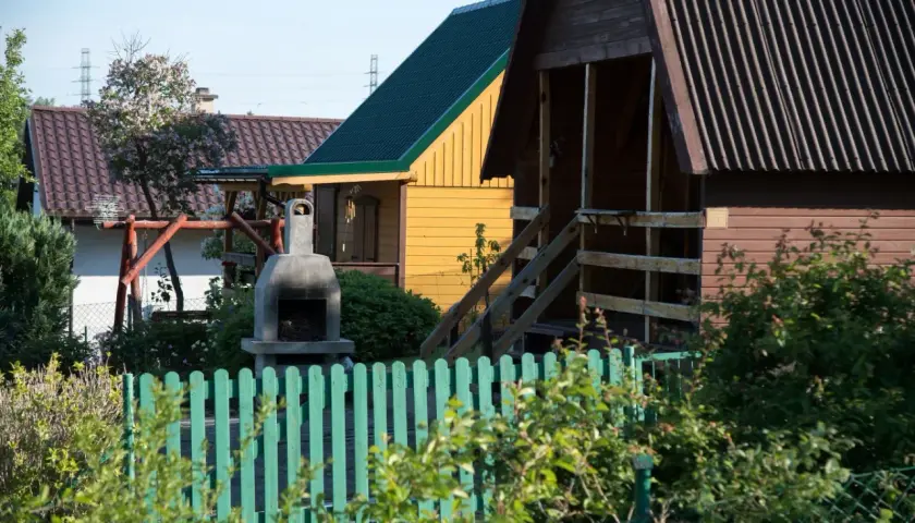 Ogródek z domkami, grillem i huśtawką. Czy myśliwy może strzelać w kierunku budynku? Nie, to niebezpieczne.