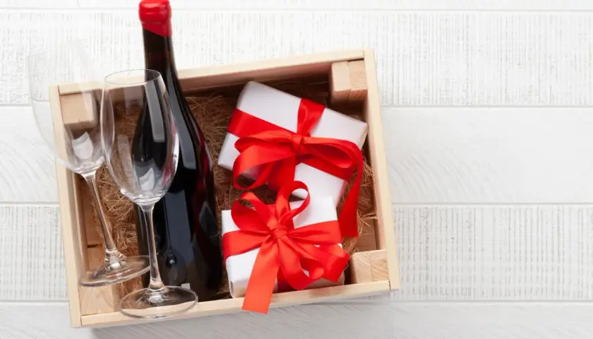 Cadeau gourmand : une bouteille de vin rouge, deux verres et des présents emballés, prêts à être dégustés dans un domaine de Bourgogne.
