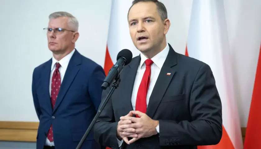 Mężczyzna w garniturze mówi do mikrofonu, obok stoi drugi mężczyzna. Dyskutują, dlaczego prezydent chce zwiększenia budżetu na Biuro Bezpieczeństwa Narodowego o 15 procent.