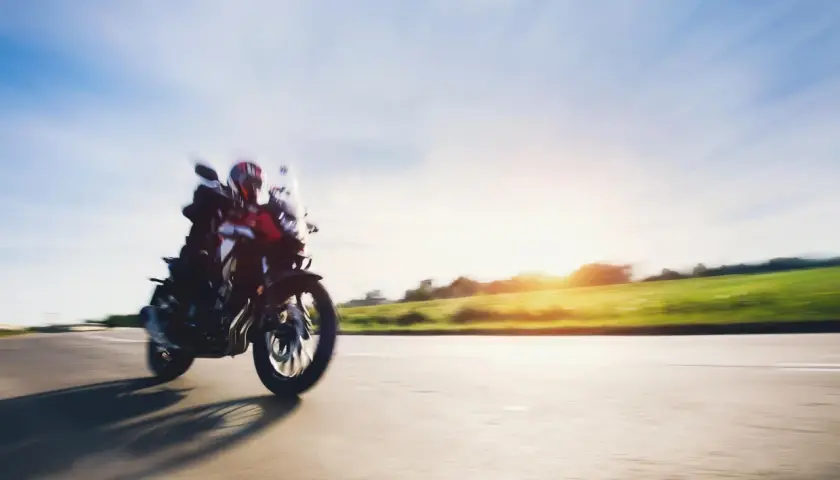 Motocyklista w kasku pędzi drogą, ciesząc się pięknym zachodem słońca. To idealny **sezon motocyklowy**!