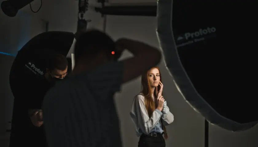 Sesja zdjęciowa w studiu. Fotograf z aparatem, modelka i oświetlenie. Inspiracja dla blogi o fotografii.