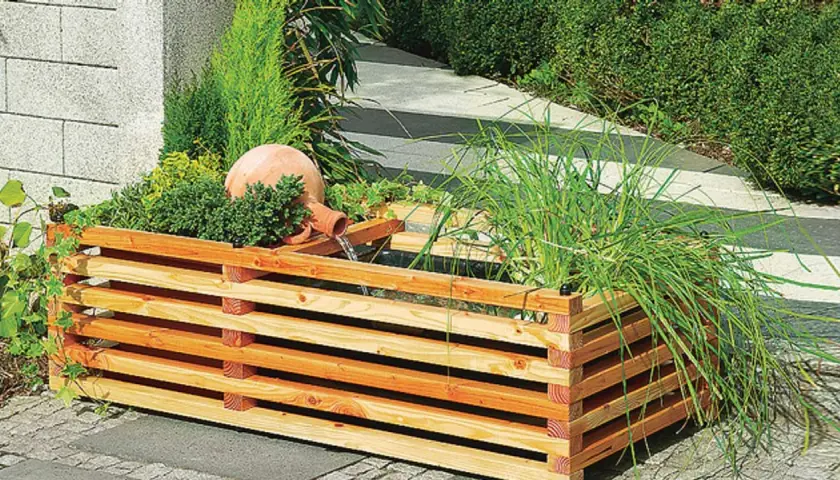 Ein **gartenbrunnen selber bauen** ist mit diesem rustikalen Holzgefäß und der Terrakotta-Kugel leicht gemacht. Wasser plätschert beruhigend.